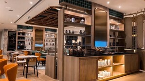 A modern restaurant with a central bar area, multiple seating options, and a variety of decorative items on display. - The Quarter Chaophraya by UHG (Bangkok)
