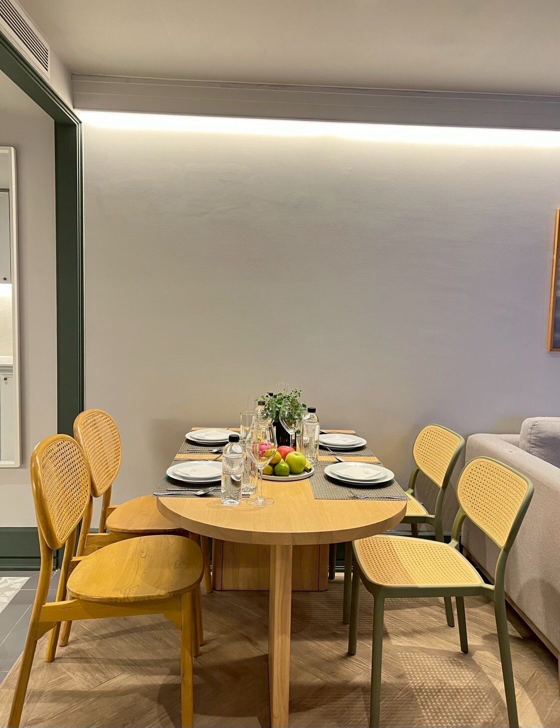 A dining area with a round table, six chairs, and a fruit centerpiece.
