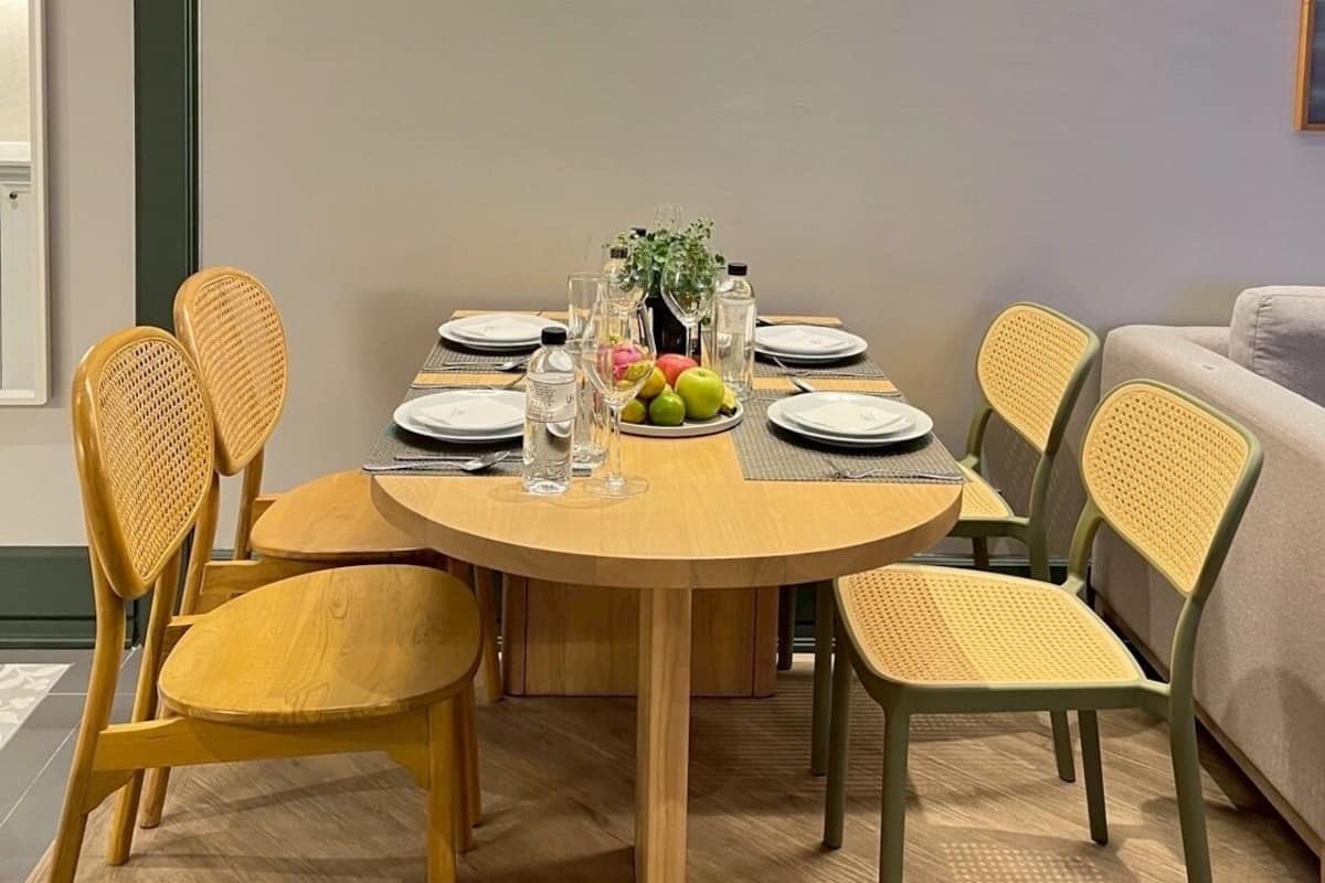A dining area with a round table, six chairs, and a fruit centerpiece.