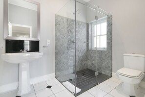 Un baño con cabina de ducha de vidrio, un lavamanos blanco y un inodoro.