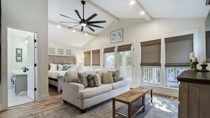 A spacious living room with a sofa, coffee table, and a ceiling fan. There are large windows with blinds and a view of the outside. - Coastal home w/ bikes & fenced yard (Santa Rosa Beach)