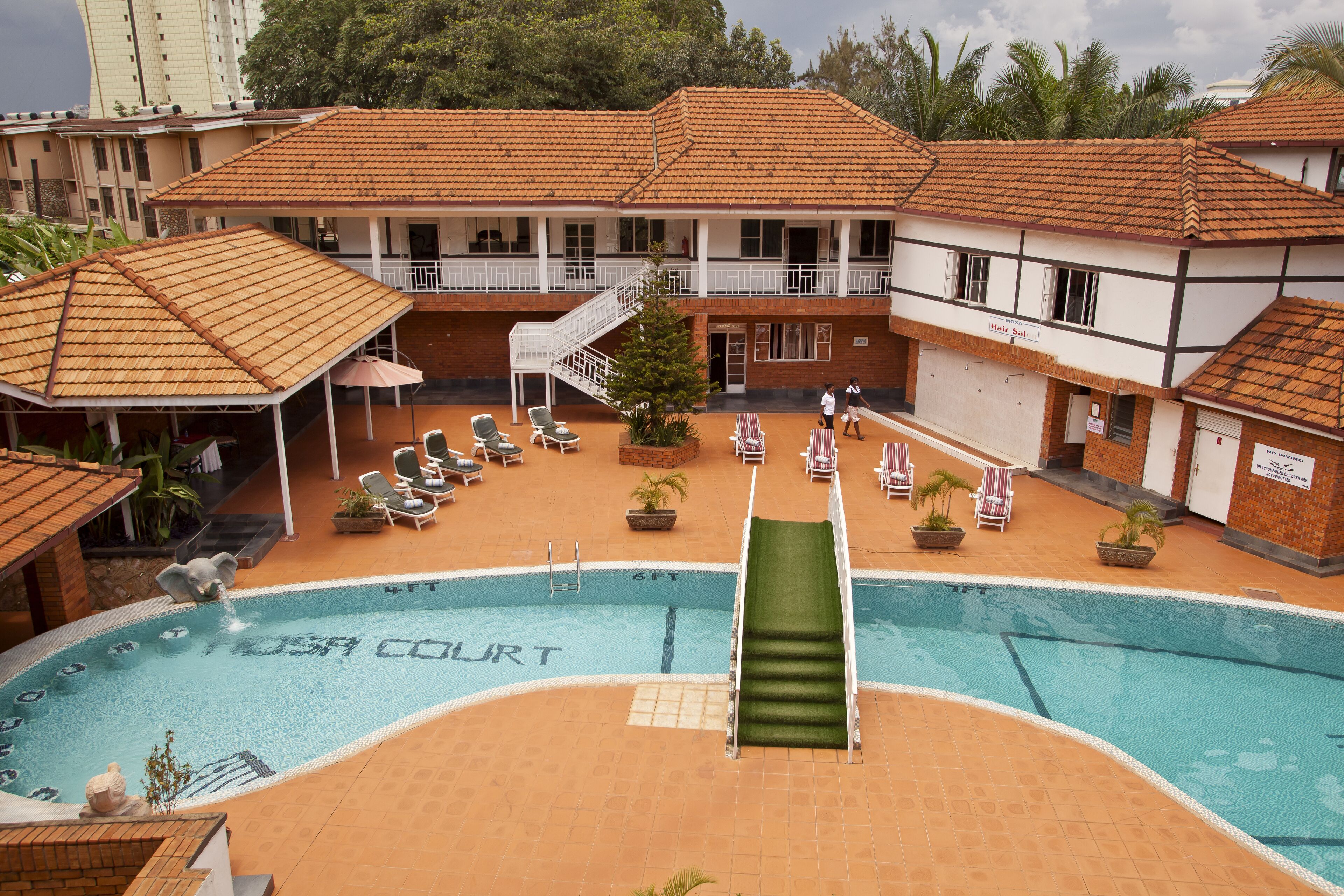 A swimming pool with a slide, lounge chairs, and a covered seating area.