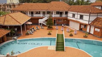 A swimming pool with a slide, lounge chairs, and a covered seating area.