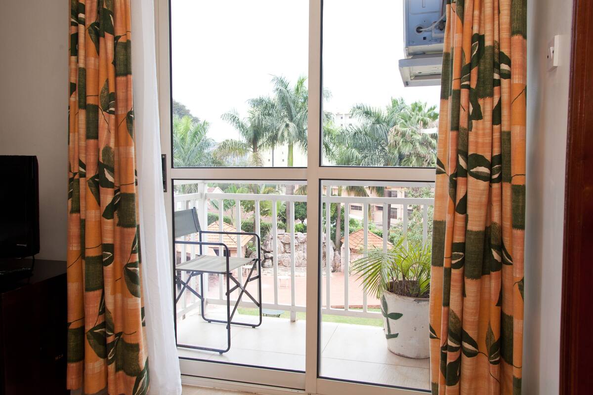 A balcony with a white railing, a table, and a chair. There is a potted plant on the balcony.