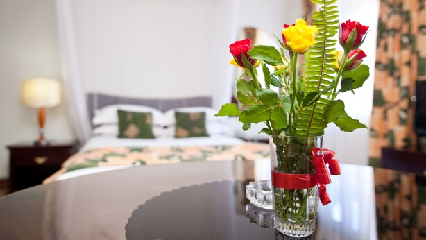 A clear glass vase with a red ribbon on a table in a hotel room. - Mosa Court Apartments (Kampala)