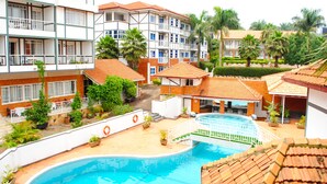 Un hotel con piscina, varios balcones y vegetación circundante.