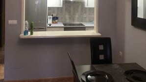 Une cuisine dotée d’une fenêtre intégrée, d’une horloge et d’un coin repas avec une table et des chaises.
