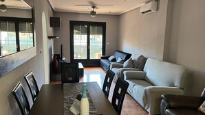 Un salon moderne comprenant un coin repas, un canapé, un téléviseur et un ventilateur de plafond.