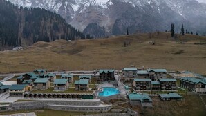 Un complejo turístico con varias edificaciones, una piscina y vistas a montañas nevadas.