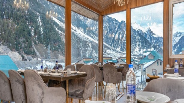 Un comedor con vistas a la montaña, techo de madera y sillas modernas.