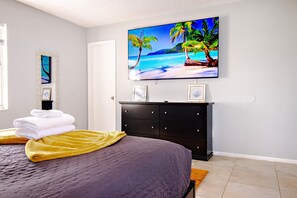 A bedroom with a bed, a TV on the wall, a dresser, and a framed picture. - Brand NewPainted Vacation Hse NrUCF PetsOK Fenced (Orlando)