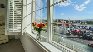 A room with a large window overlooking a parking lot and a clear sky.