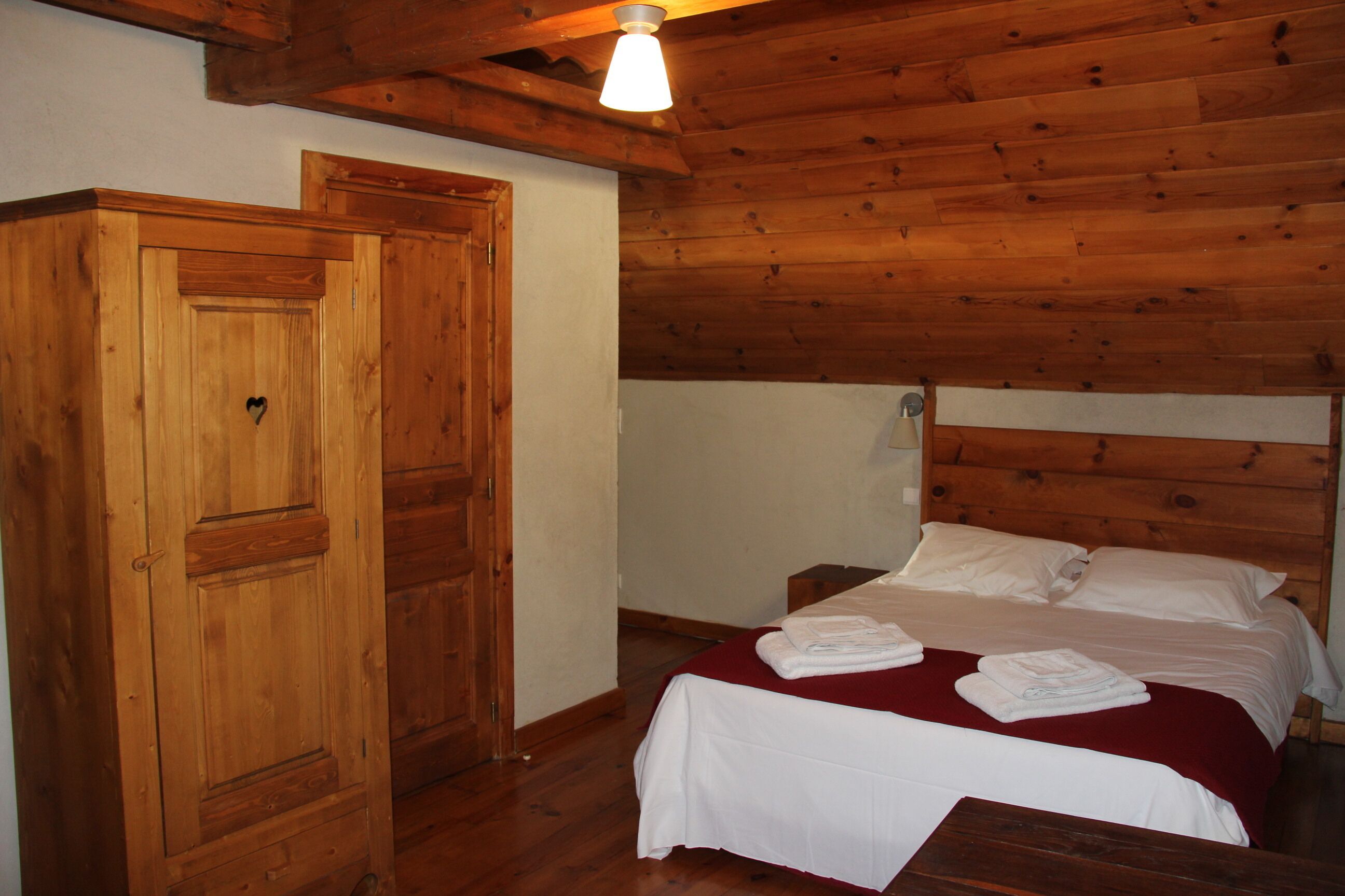 Una stanza con pannelli in legno, un letto, un armadio di legno e una lampada a soffitto.
