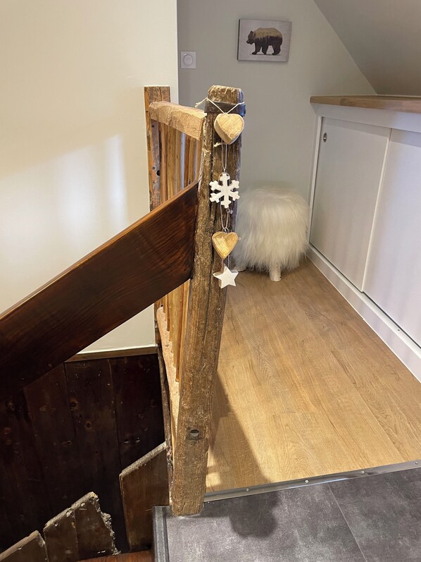 Una escalera de madera con un diseño rústico, una alfombra blanca y mullida en el suelo y un adorno de pared con temática de oso.