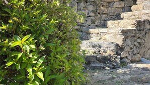 Un edificio de piedra con una ventana pequeña y una escalera que sube a un nivel superior.