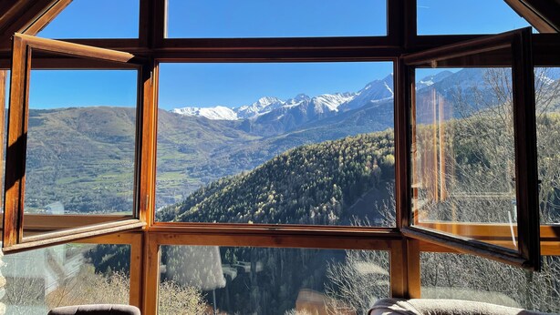 Una habitación con amplios ventanales que ofrecen vista a la montaña.