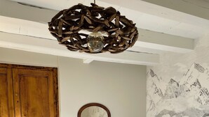 Un dormitorio con un armario de madera, una mesita de noche con espejo, una cama con ropa blanca y un mural de un paisaje montañoso en la pared.