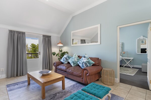 A living room with a brown leather sofa, a wooden coffee table, and a teal ottoman.