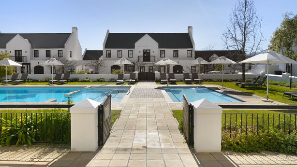 A large building with a swimming pool and outdoor seating area. - Winelands Golf Lodges 40 (Stellenbosch)