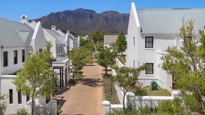 A row of white buildings with a mountain in the background. - Winelands Golf Lodges 40 (Stellenbosch)