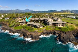 A coastal hotel with multiple buildings, a rocky shoreline, and a view of the ocean and mountains in the background. - MA 1-310 AC, Fantastic Views, 2 b Loft, 2 1/2 Bath (Koloa)