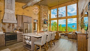 A spacious kitchen with a large island, wooden cabinets, and a stone accent wall. - 🐻Gatlinburg Mountain Romance: Secluded, Honeymoon, Outdoor Fireplace, Hot Tub🏞 (Gatlinburg)