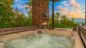 A hot tub with a stone wall backdrop, surrounded by lush greenery and a scenic view. - 🐻Gatlinburg Mountain Romance: Secluded, Honeymoon, Outdoor Fireplace, Hot Tub🏞 (Gatlinburg)