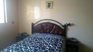 Un dormitorio con una cama, una mesita de noche, un aparador e imagen colgada en la pared.