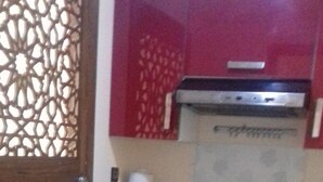 Una cocina con microondas, cafetera y refrigerador decorado con motivos florales.