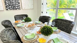 A dining table set with wicker chairs, green napkins, and a potted plant.