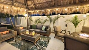 A cozy lounge area with wicker furniture, a thatched ceiling, and ambient lighting.