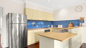 Eine moderne Küche mit einem Edelstahl-Kühlschrank, beigen Schränken, blauen Fliesen und einer Holz Arbeitsplatte.