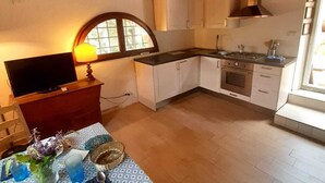 A cozy kitchen with wooden beams, a TV, and a dining area with a table set for two. - Charming 4-bed Cottage 15 Minutes From Florence (Impruneta)
