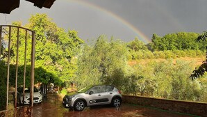A car parked on a wet driveway with a rainbow in the background. - Charming 4-bed Cottage 15 Minutes From Florence (Impruneta)