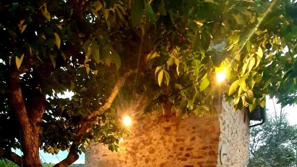 An outdoor dining area with a stone wall, wooden chairs, and a table set for two. - Charming 4-bed Cottage 15 Minutes From Florence (Impruneta)