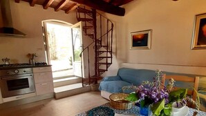 A cozy dining area with a patterned tablecloth, a blue sofa, and a kitchen in the background. - Charming 4-bed Cottage 15 Minutes From Florence (Impruneta)