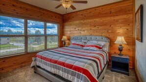 A bedroom with a large bed, two bedside tables with lamps, a ceiling fan, and a window with blinds. - Cozy Golf course condo with A/C (pagosa springs)