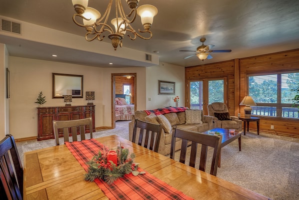 A dining area with a wooden table, chairs, a chandelier, and a ceiling fan.