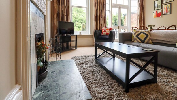 A living room with a fireplace, a television, a sofa, and a coffee table. - Magpies (St Leonards-On-Sea)