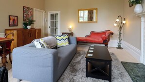 A living room with a grey sofa, a red armchair, a coffee table, a fireplace, and a mirror on the wall. - Magpies (St Leonards-On-Sea)