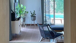 Un intérieur moderne comprenant un coin repas, un espace salon avec un canapé et une vue sur une piscine extérieure.
