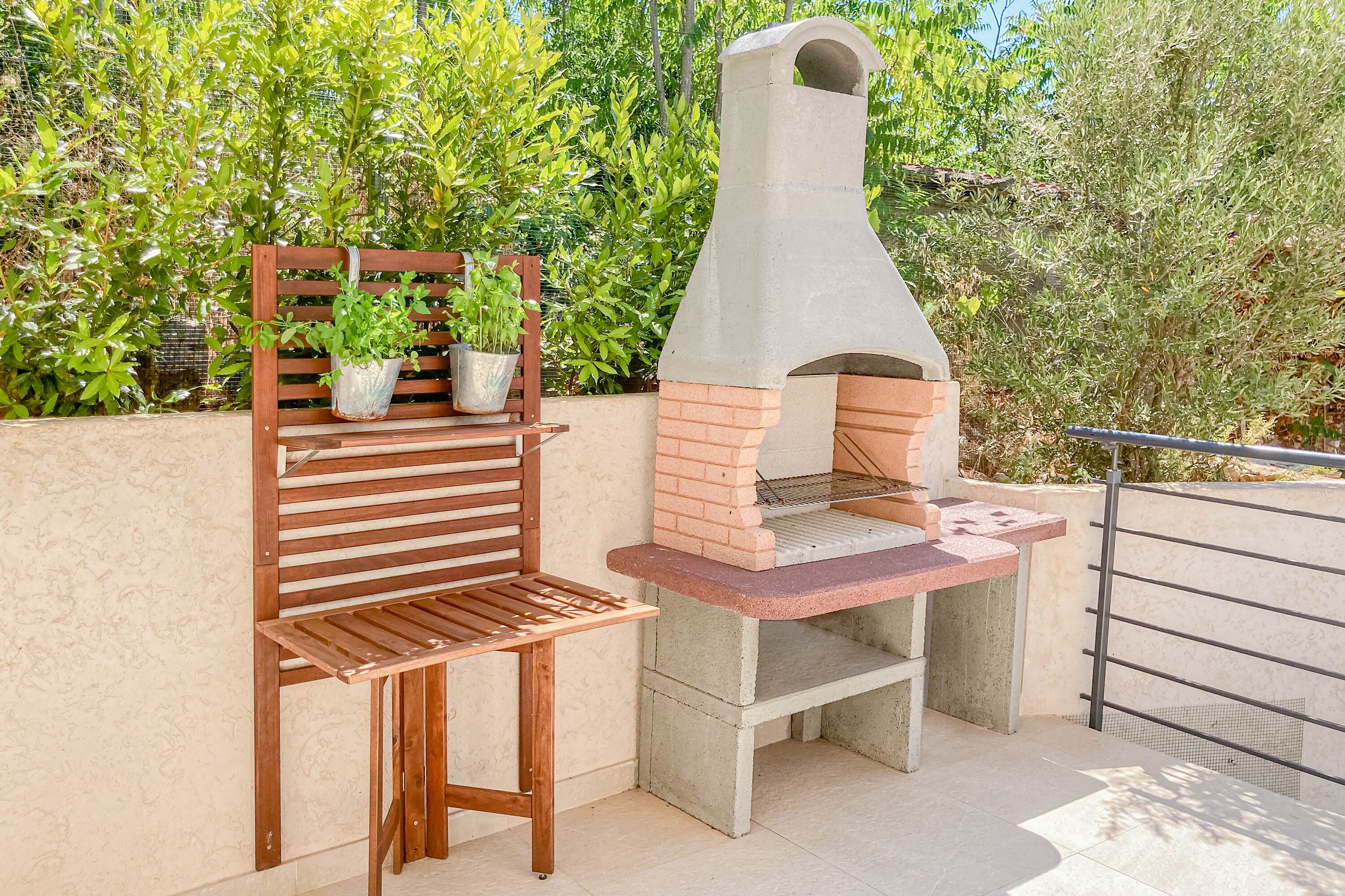 An outdoor patio with a brick oven and a wooden bench.