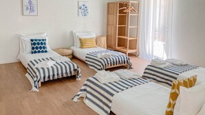 Une chambre avec trois lits, une armoire en bois et deux tableaux accrochés au mur.