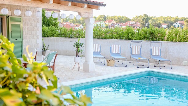 Un espace piscine aménagé avec des chaises longues, une table et des plantes en pot.