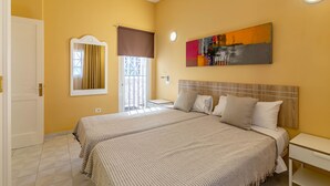 A hotel room with two beds, a large window with curtains, a painting on the wall, and a bedside table. - Vista Verde Adult Only (San Bartolomé de Tirajana)