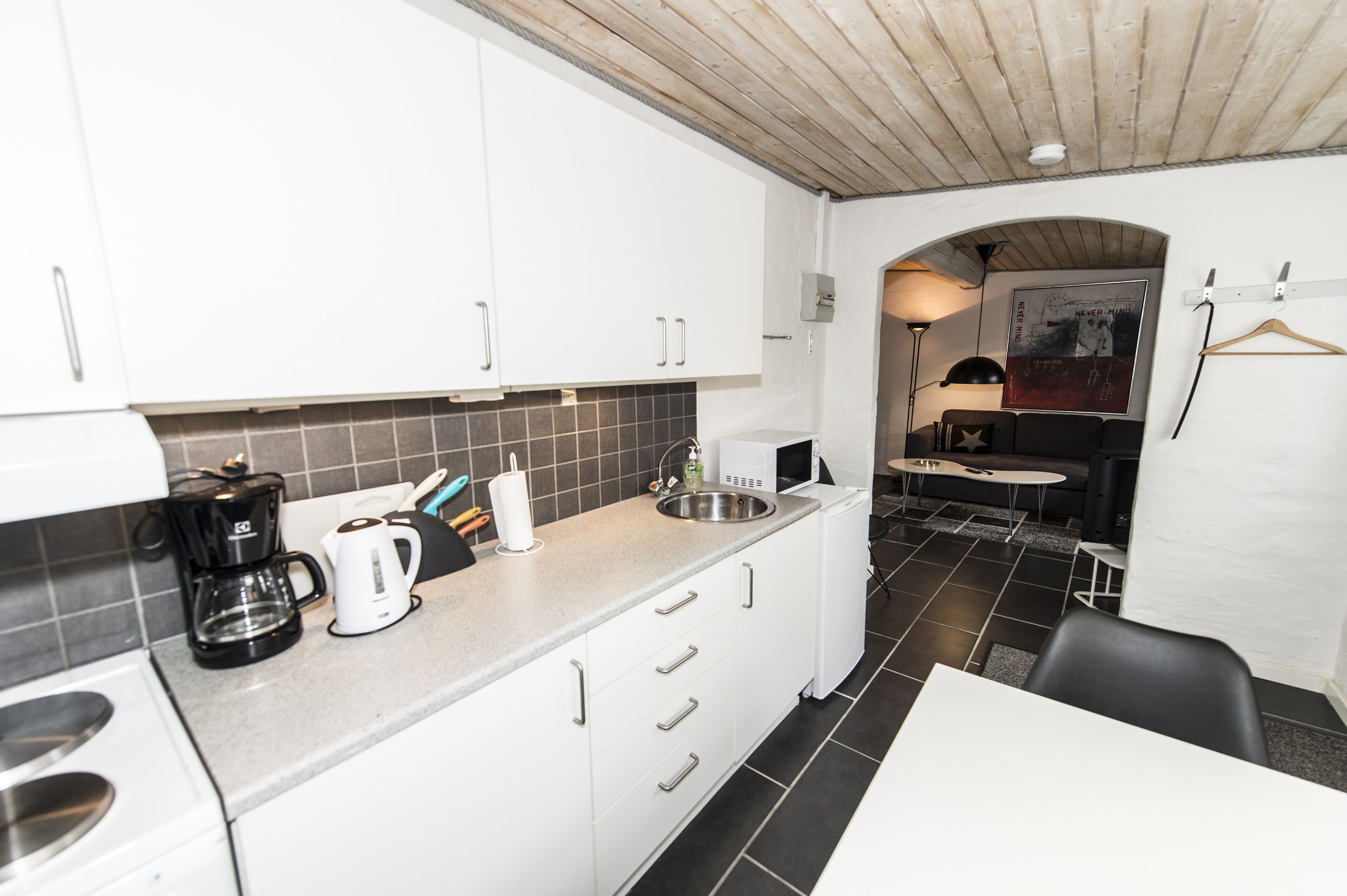 A compact kitchen with white cabinets, a coffee maker, and a sink.