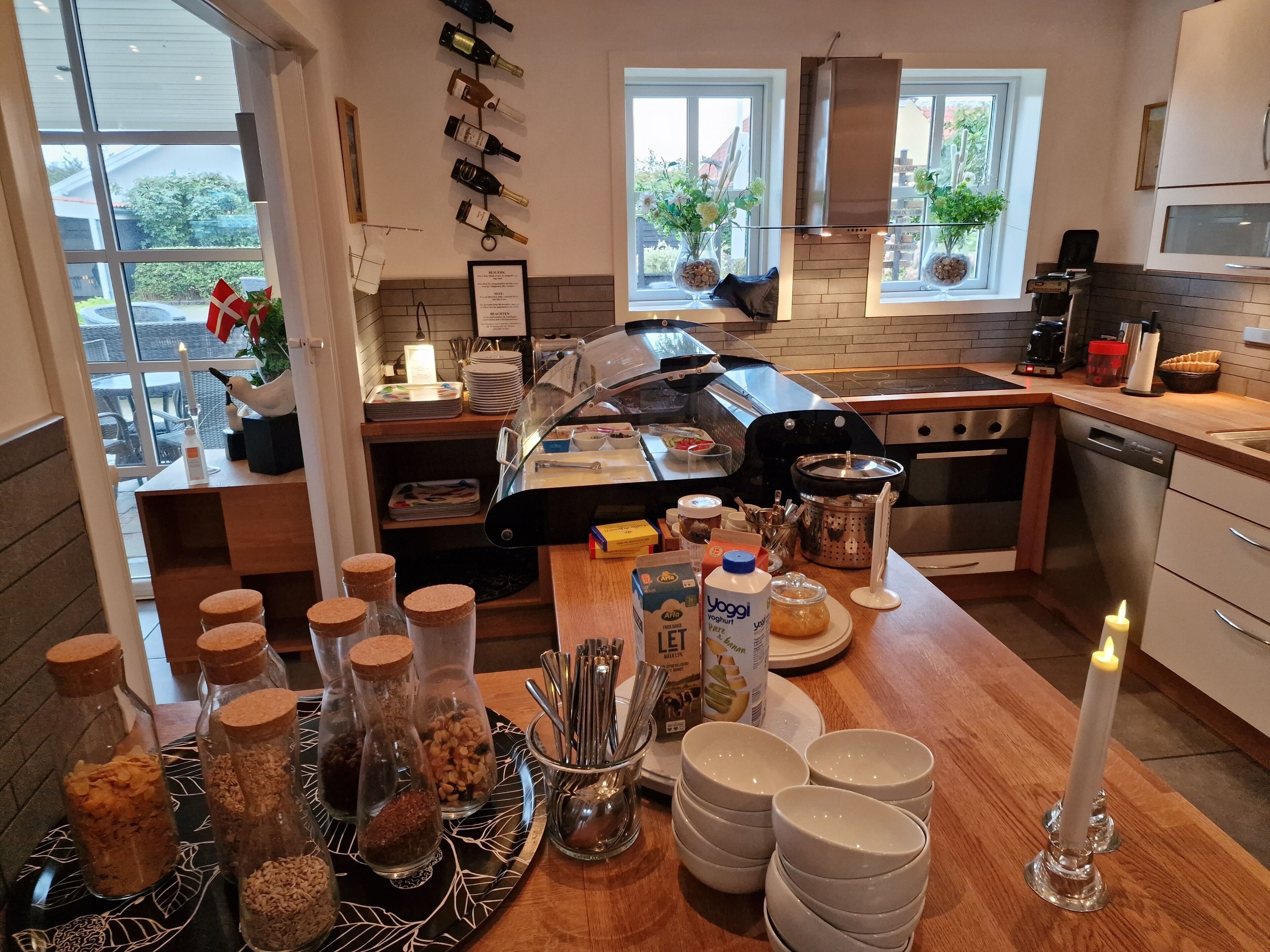 A modern kitchen with a central island, stainless steel appliances, and a view of the outdoors.