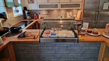 Un comptoir pour le petit-déjeuner avec divers aliments, une machine à café et un réfrigérateur.