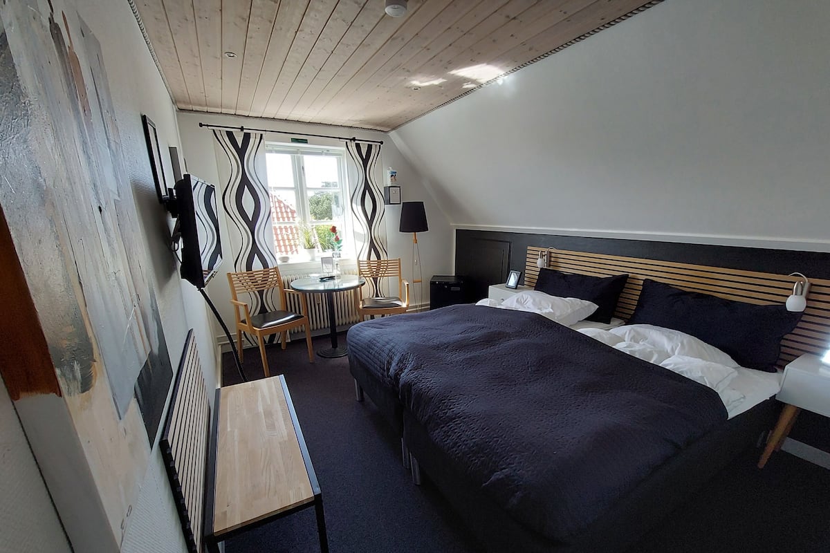 A bedroom with a large bed, a bedside table, a chair, and a small table.