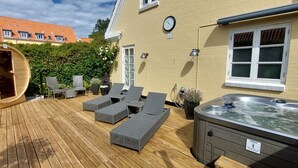 Una terraza de madera con sillones de descanso, un jacuzzi y una sauna.